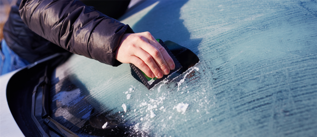 gefrorene Frontscheibe eines Autos wird freigekrazt